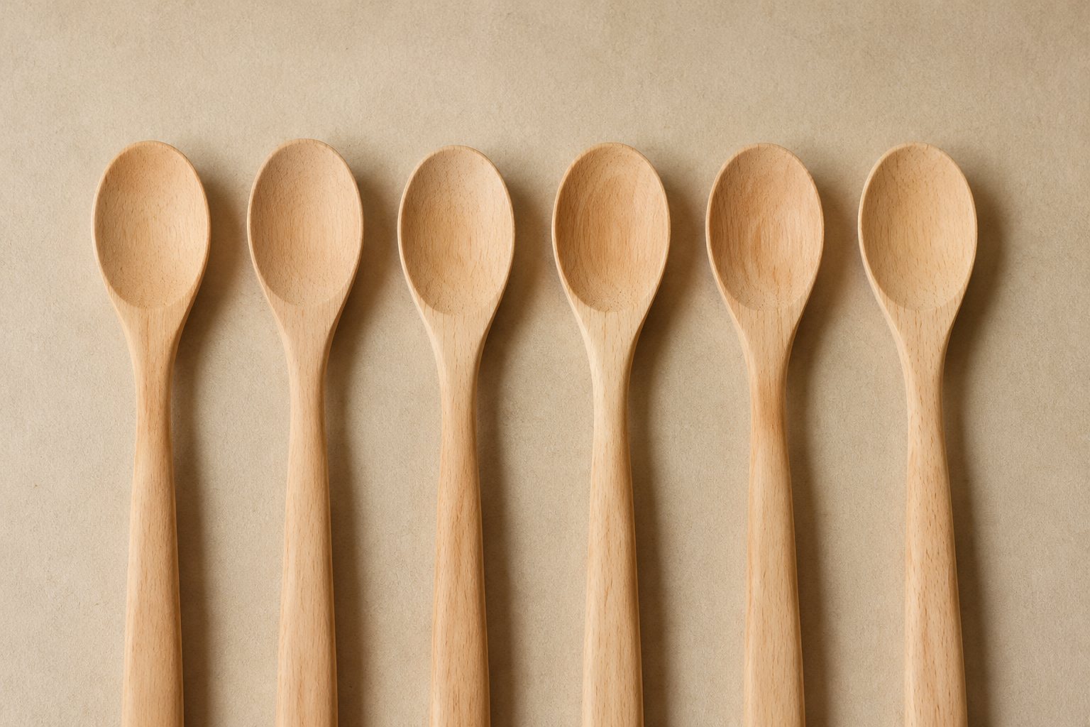Illustration: pale beech wooden spoons and spatulas in a row on a workshop bench